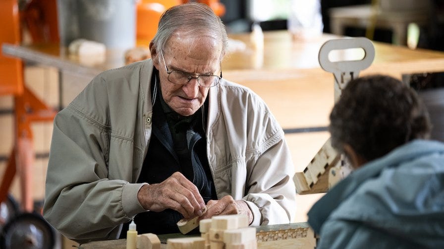 Ken's father, Robert, helps put axels and wheels on the toy cars.